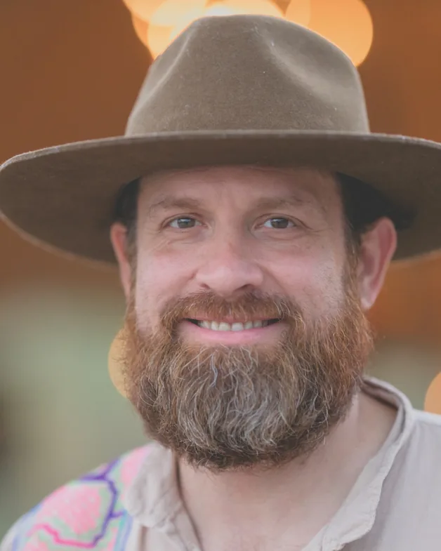 Joshua Tarbutton, smiling, in a wide-brimmed hat